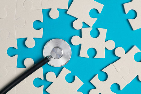 Jigsaw puzzle pieces and stethoscope on blue background.の写真素材