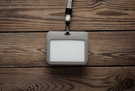 Blank plastic Id card badge with belt on wooden table. Template for designの写真素材