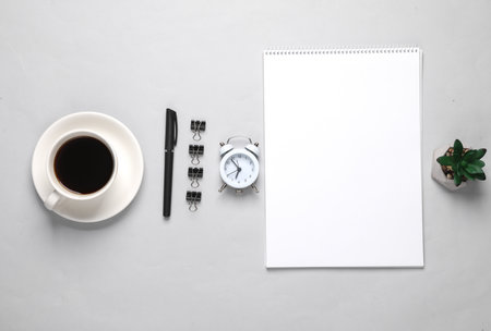 Business layout with sketchbook and coffee cup, alarm clock on gray background. top viewの写真素材