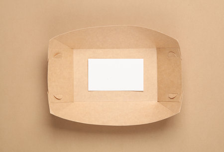 Craft paper square plate with a business card on a beige background
