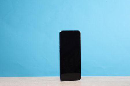 Smartphone standing on the table, blue backgroundの写真素材