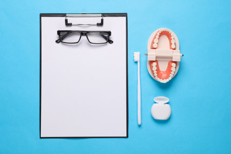 Caring for the oral cavity, a visit to the dentist. Clipboard with jaw, toothbrush and dental floss on blue background. medicine conceptの写真素材