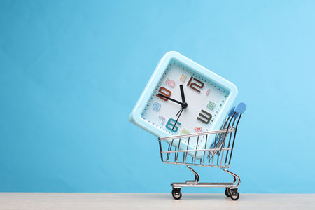 Supermarket trolley with clock on the table, blue background