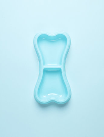 Dog bowl for food in the shape of a bone on blue background