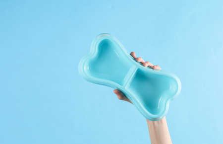 Hand holding a dog bone shaped plate on a blue backgroundの写真素材