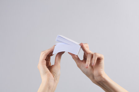 Stack of square memo papers in female hands, gray background. Business concept