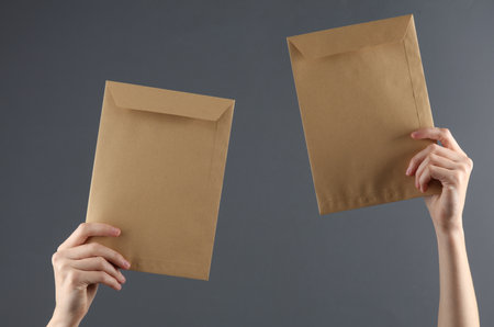 Female hands hold craft mail envelopes on a dark background