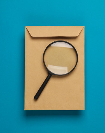 Craft mail envelope with a magnifying glass on a blue backgroundの写真素材
