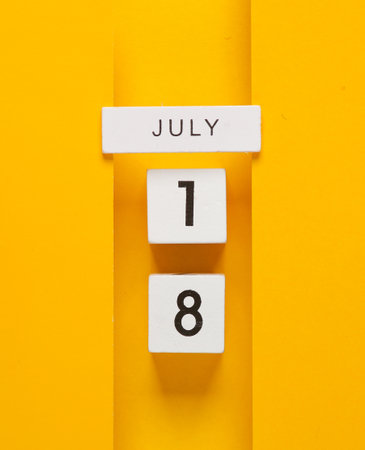 White calendar cubes with date july 18 on yellow background. creative layoutの写真素材