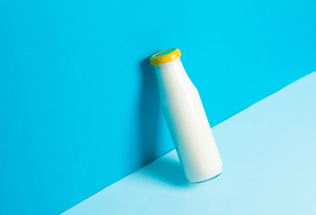Glass bottle of yogurt on a blue background