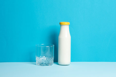 Bottle of yogurt and glass on a blue backgroundの写真素材