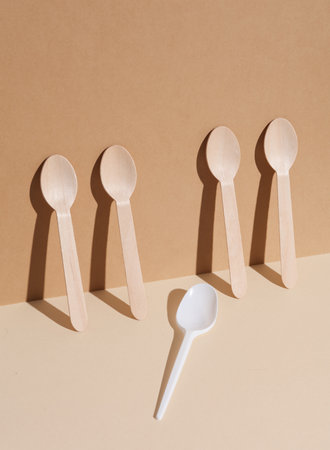 Plastic and wooden spoons on a beige background with shadow. Eco concept, plastic free, food. creative layoutの写真素材