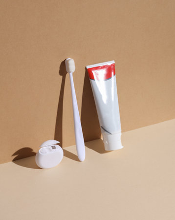 White toothbrush with toothpaste and dental floss on a beige-brown background with a shadow. dental care. minimalist composition. creative layoutの写真素材