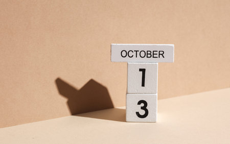 Wooden white block calendar with date october 13 on beige background with shadow. Creative layout, planning, holidaysの写真素材