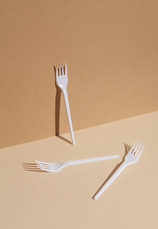 White plastic forks on a beige background with a shadow. creative layoutの写真素材