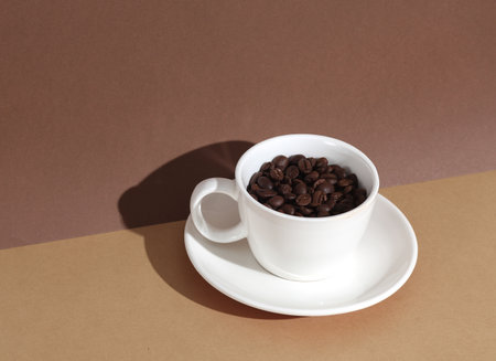 Ceramic cup with coffee beans on a brown backgroun with shadow. Creative layoutの写真素材