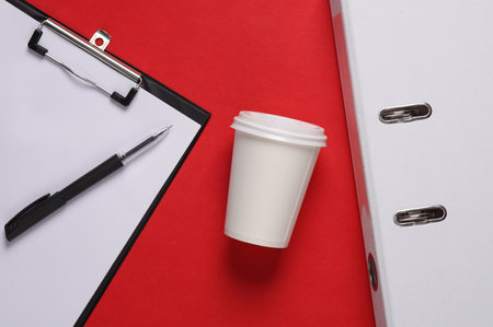 Conceptual business photo. Clipboard and white cardboard coffee cup folder on red background....