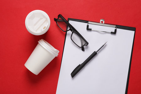 Conceptual business photo. Empty clipboard with pen, eyeglasses and a coffee cups on gray background. Template for design, mockup. Top viewの写真素材