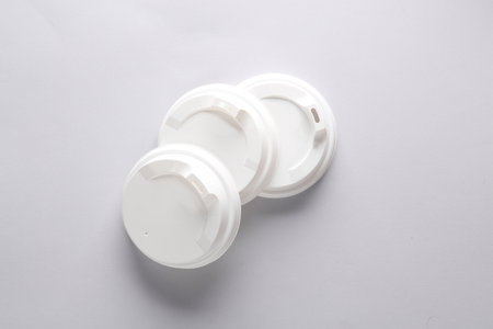 White plastic disposable lids for cup on gray background. Mockup, template for design