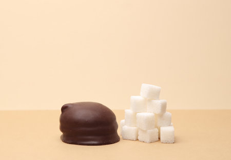 Chocolate candy and sugar cubes on a beige backgroundの写真素材