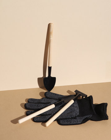 Set of miniature garden tools (rakes, shovels) and working gloves on brown beige background. Creative layoutの写真素材