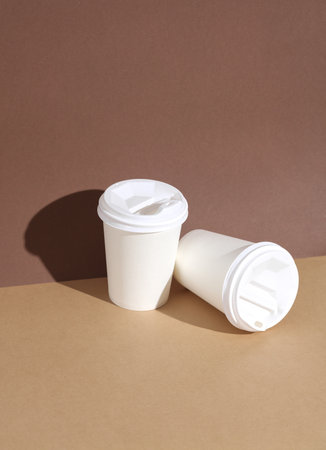 white Disposable cardboard coffee cups on brown background with shadow. Creative layoutの写真素材