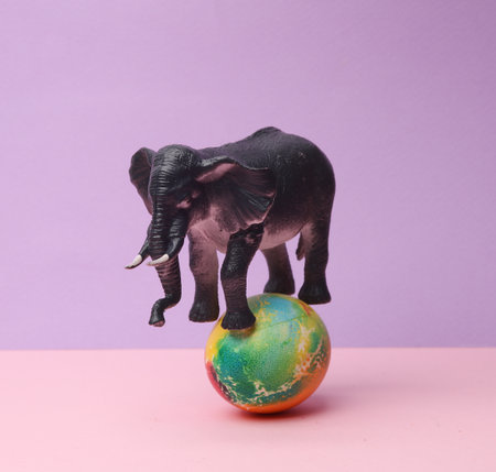 Toy elephant is balancing on a colored Easter egg. Minimal easter still lifeの写真素材