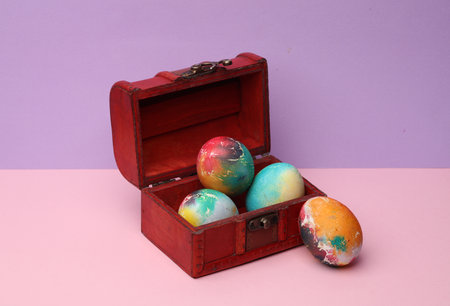Chest with colored eggs on a pastel background. Conceptual Easter photoの写真素材