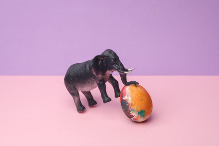 elephant with colored egg on a pastel background. Conceptual easter photo