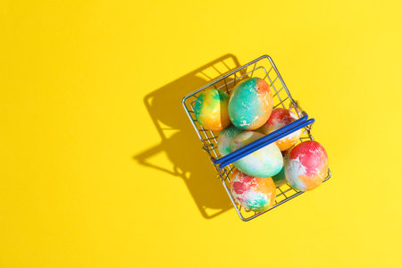 Supermarket basket with Easter eggs on yellow background. Minimalism Easter still lifeの写真素材