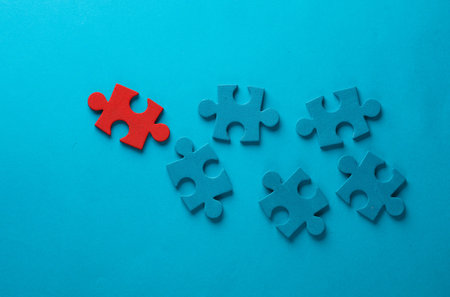 Blue and red jigsaw puzzle pieces on blue background. Business conceptの写真素材