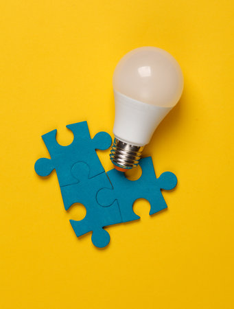 Puzzle pieces with a light bulb on a yellow background. Business concept