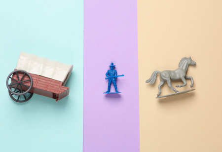 Figurine of a cowboy, cart with horses on pastel background. Creative layoutの写真素材