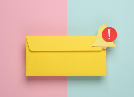 Yellow paper envelope with bell and red notification symbol on pink blue background. Message alert.の写真素材