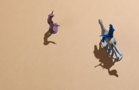 Wild west scene. plastic cowboy and american Indian on horse, beige background with shadowの写真素材