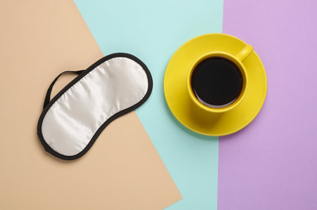 Sleeping mask and a cup of coffee on a pastel background. Insomnia. Top viewの写真素材