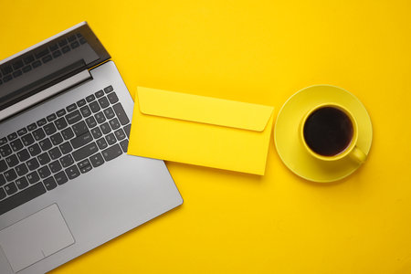 Laptop, Yellow ceramic cup with coffee and envelope on yellow background. Top view. Flat lay. Business conceptの写真素材