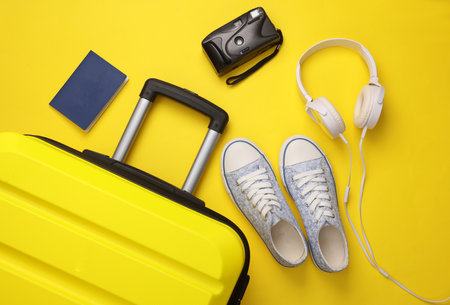 Yellow suitcase, luggage with travel accessories on yellow background. Summer vacation, travel, relocation concept. Top view. Flat layの写真素材
