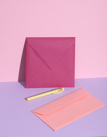 Creative layout with purple and pink envelopes with pen on pastel background.