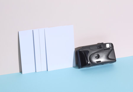 Creative travel layout. Retro plastic camera and mpty photographs on pastel background with shadow. Minimalismの写真素材