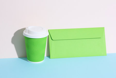 Creative layout with green coffee cup and envelope on pastel bright background. Minimalismの写真素材
