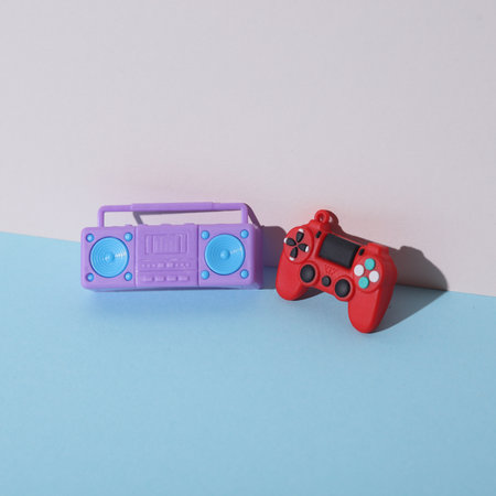 Miniature boombox tape recorder and gamepad on a pastel background. Creative layout