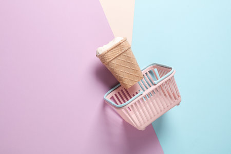 Ice cream waffle cone in mini supermarket basket on pastel backgroundの写真素材