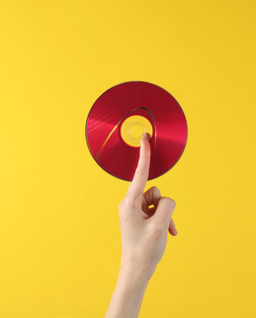 Hand holding cd disk on yellow background