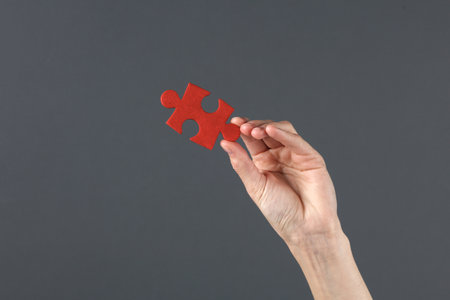 Hand holding red puzzle piece on dark background. Business concept, teamwork