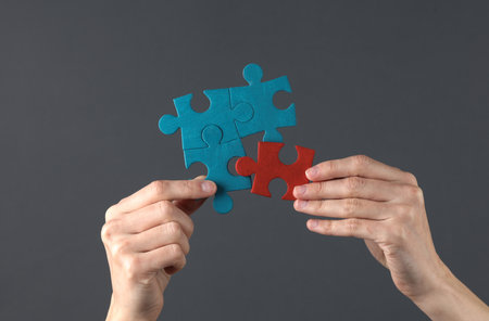 Hand holds puzzle pieces on a dark background. Business concept, teamwork