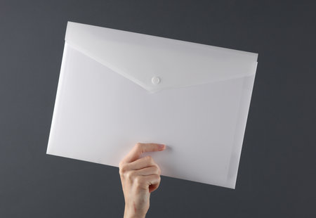 White plastic envelope folder in hand on dark backgroundの写真素材