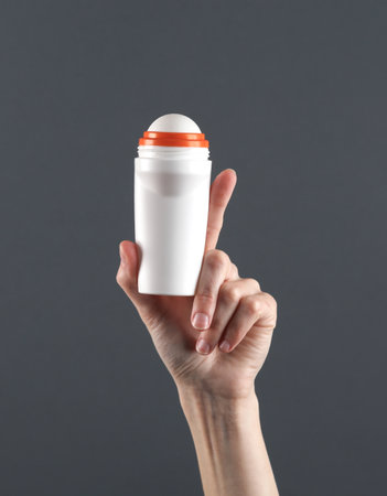 Woman's hand holding antiperspirant stick on dark gray backgroundの写真素材