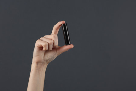 Female hand holding dominoes on a dark gray backgroundの写真素材