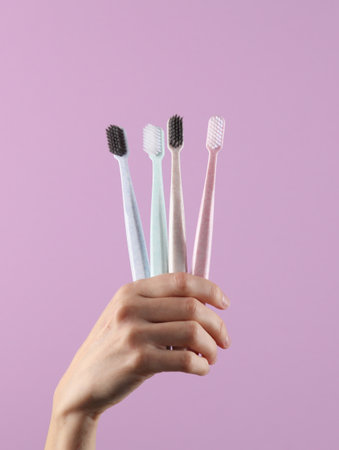 Hand holds toothbrushes on pastel background. Caring for teeth, oral hygiene conceptの写真素材